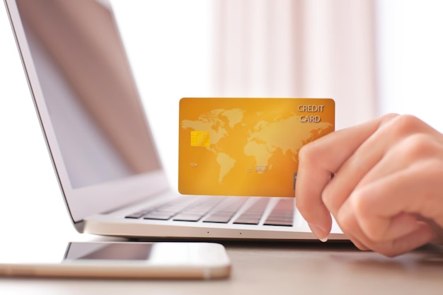 Woman with credit card and laptop at table closeup