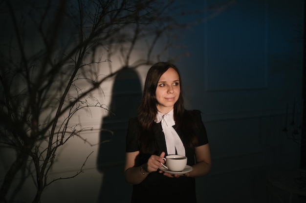 Woman with cup of coffee in dark place