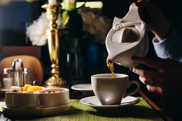 A woman with a cup of hot tea in her hands sits in the restaurant The girl drinks aromatic tea Enjoy the moment take a break