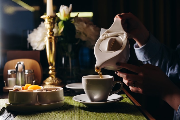 A woman with a cup of hot tea in her hands sits in the restaurant The girl drinks aromatic tea Enjoy the moment take a break