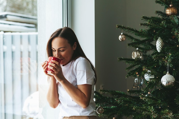 Woman with cup near Christmas tree