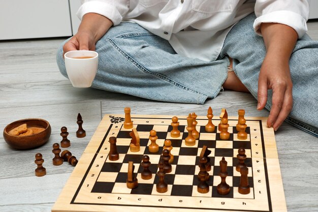 woman with a cup of tea playing chess at home