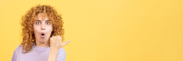 Woman with curly hair pointing surprised to the side