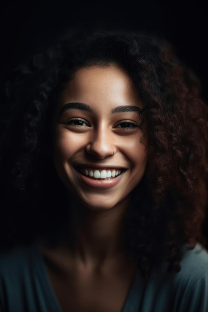 A woman with curly hair smiles in front of a black background.