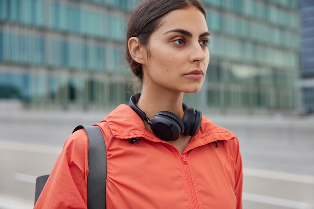 woman with dark hair dressed in sportswear going to practice yoga or have workout poses outdoors