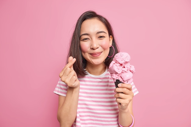 woman with dark hair makes mini heart gesture eats delicious ice cream gestures korean like sign expresses love poses