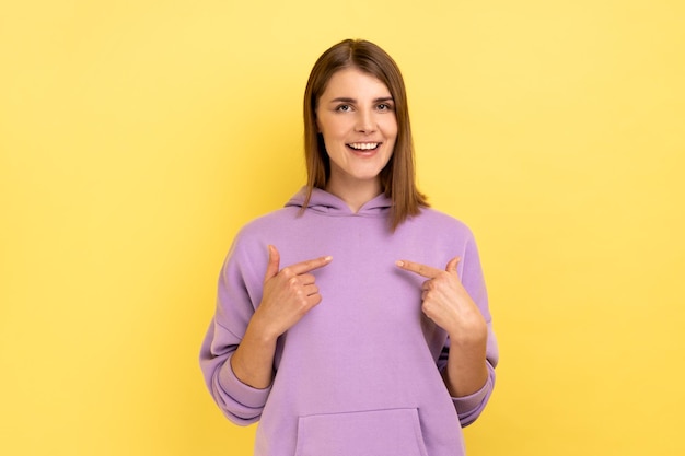 Woman with dark hair standing with amazed face and pointing herself being proud and happy