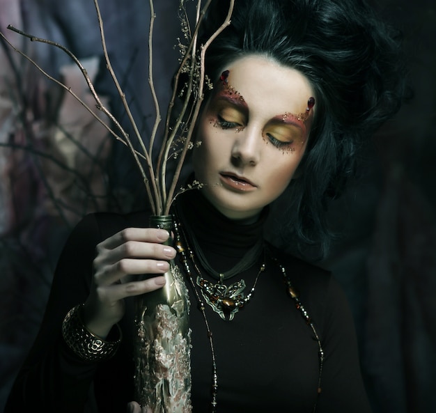 Woman with dark make up with dry branches