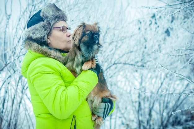 Woman with dog Pekingese in winter park