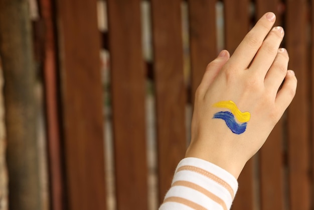 Woman with drawing of Ukrainian flag on hand outdoors closeup Space for text