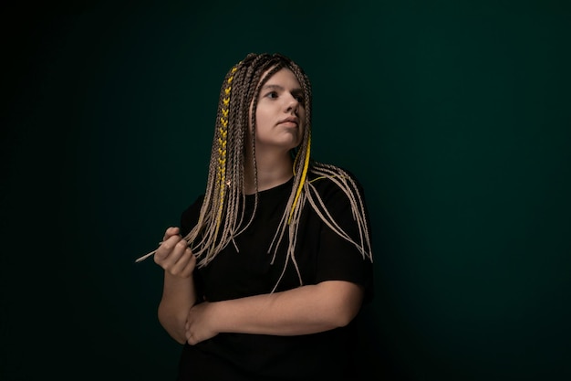 Woman with dreadlocks in front of green wall