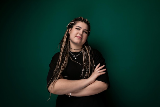 Woman with dreadlocks standing in front of green wall