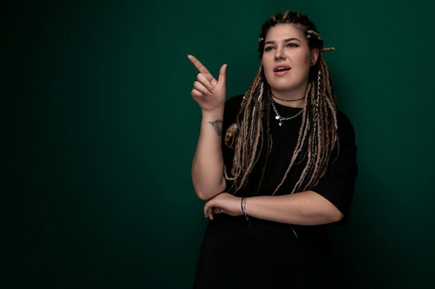 Woman with dreadlocks standing in front of green wall