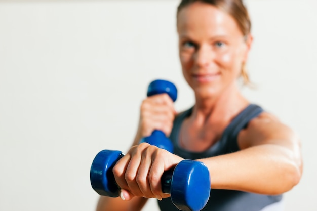 Woman with dumbbells in gym