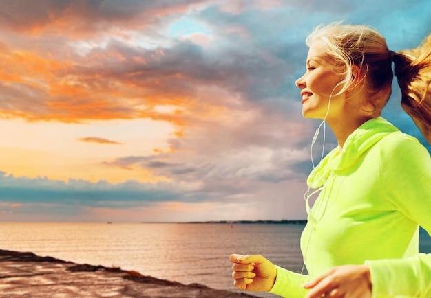 Photo woman with earphones running over sea sunset