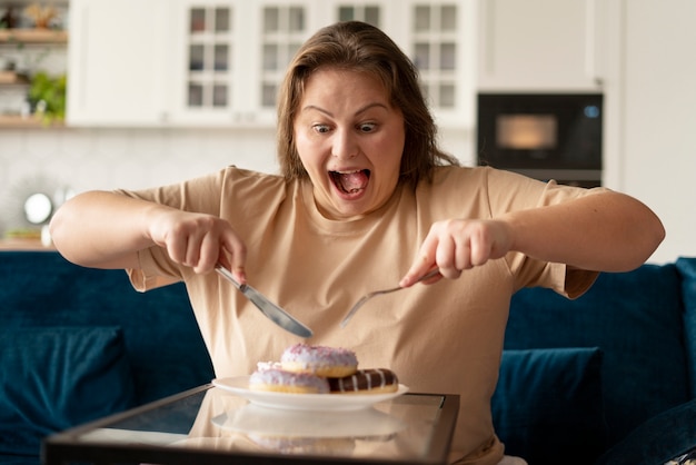 Photo woman with eating disorder trying to eat donuts