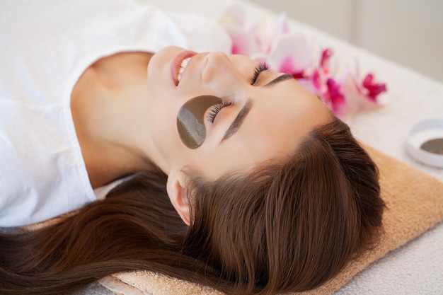 Woman With Eye Patches Relaxing In Spa Center