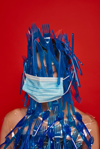 Woman with face mask covering her face and body with blue plastic tableware