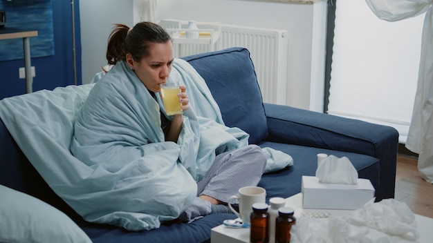 Woman with flu drinking effervescent medication with water