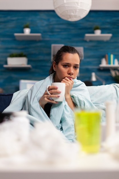 Woman with flu sitting at home drinking hot tea