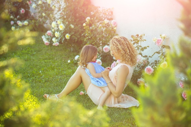 Woman with girl child at blossoming rose flowers