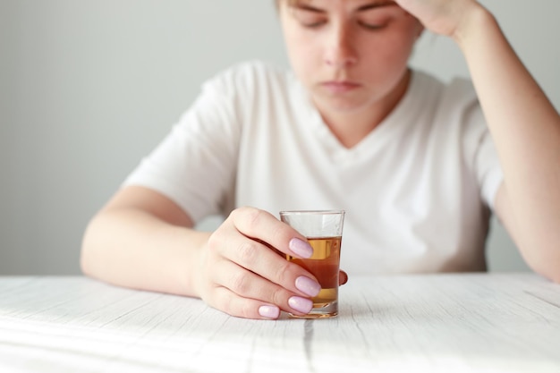 Woman with a glass of strong alcohol closeup female alcoholism