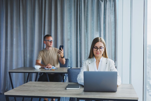 Woman with glasses at the table while working with colleagues in the office Concept of modern successful business people Man and woman sitting at wooden tables