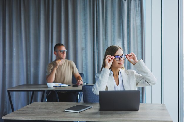 Woman with glasses at the table while working with colleagues in the office Concept of modern successful business people Man and woman sitting at wooden tables