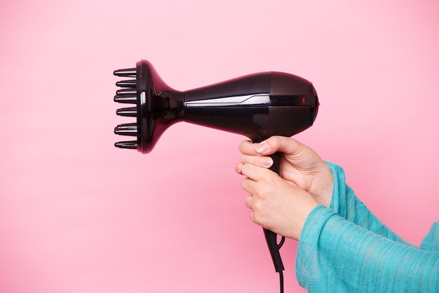 Woman with hair dryer on pink background