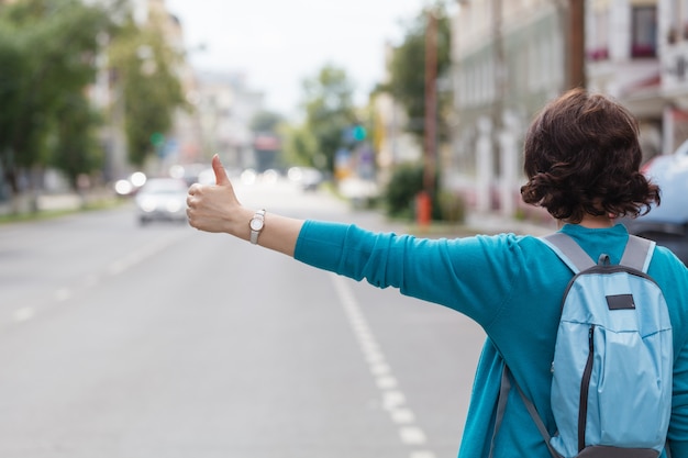 Woman with handbag hailing a taxi cab walking in city street