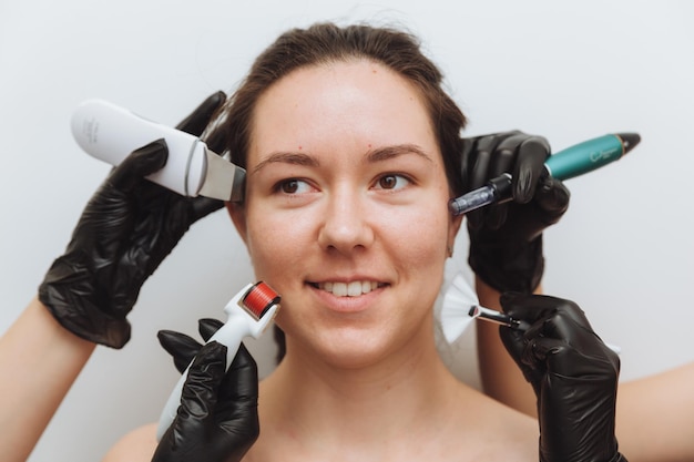 A woman with the hands of several therapists with cosmetology devices near her face a woman needs skin care skin care concept photo