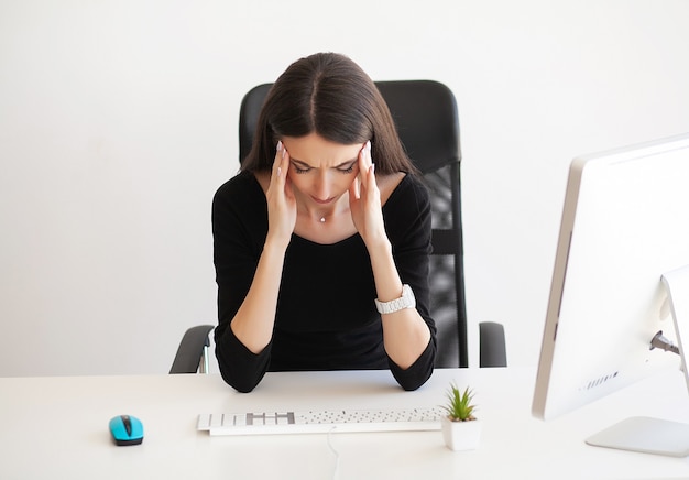 Woman with headache sitting at the table in the office