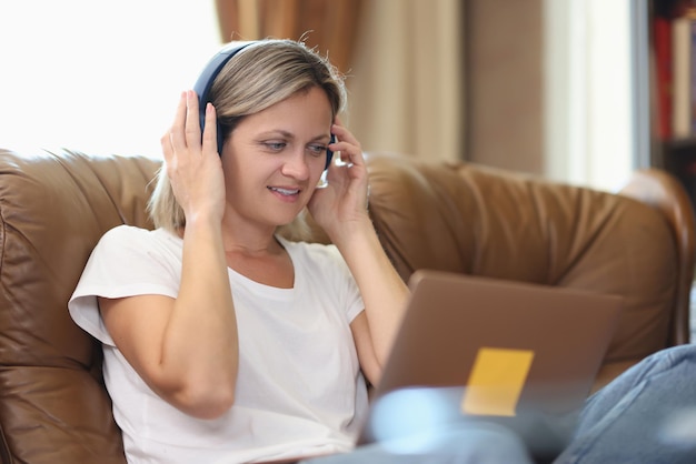 Woman with headphones and computer talking online while sitting on couch