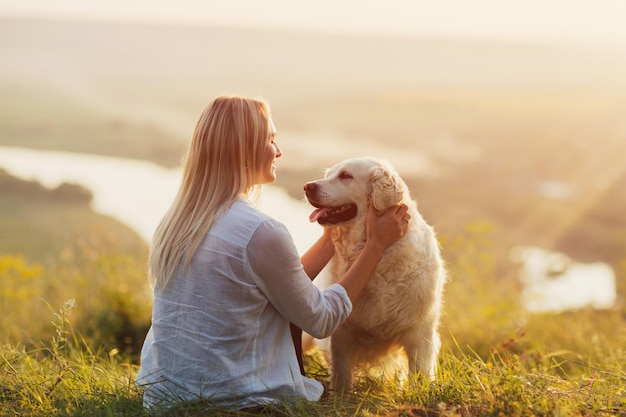 Woman with her cute dog on the hill on golden sunset