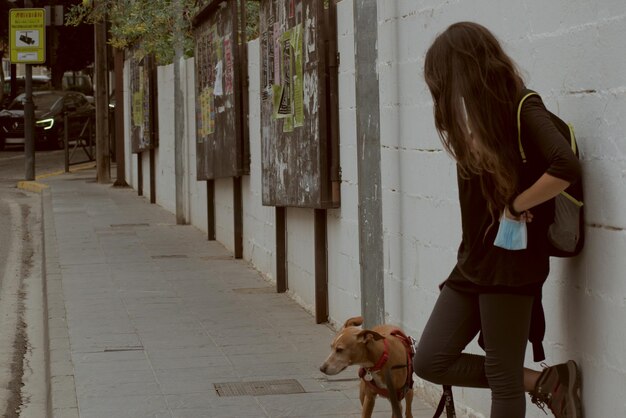 Photo woman with her dog waiting on an urban wall