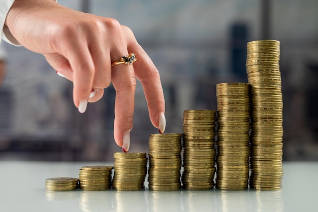 Woman with her fingers going uphill on stacks of gold coins