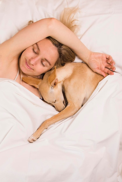 Woman with her greyhound dog in white bed