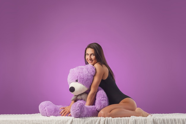 Woman with a huge teddy bear on the bed