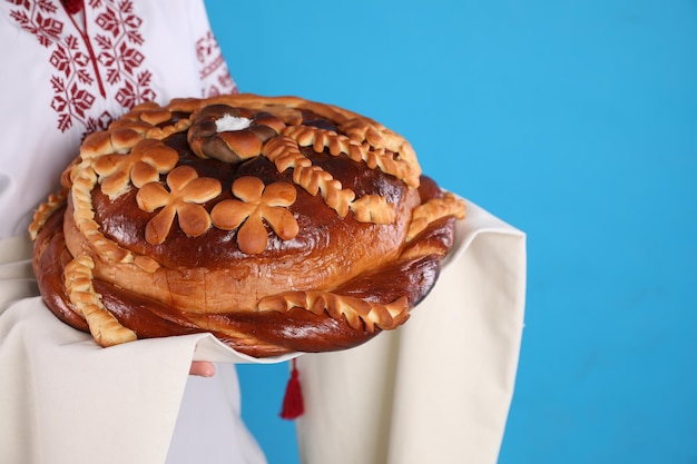 Woman with korovai on light blue background closeup Ukrainian bread and salt welcoming tradition