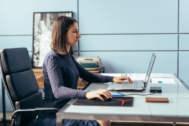 Woman with laptop at desk working or studying online.