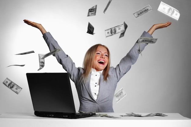 Woman with a laptop and dollar bills in the air