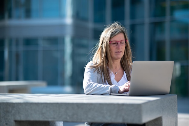 Woman with laptop outdoors in an office space with copy space