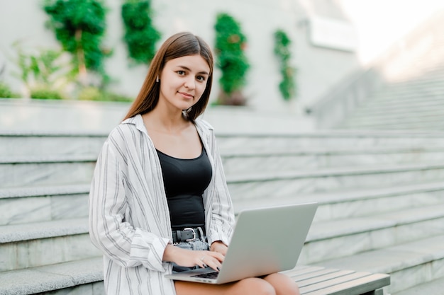 Woman with laptop outdoors working as freelancer