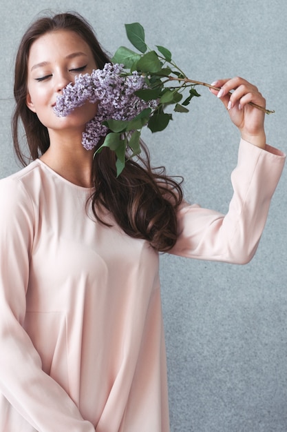 Woman with lilac brunch over gray background. Studio shot.