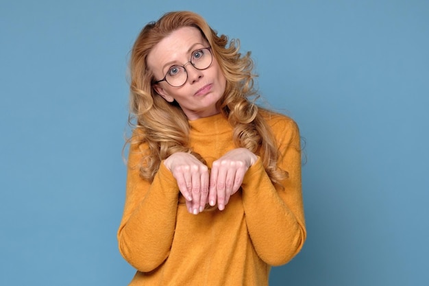 Woman with long blonde hair showing hare paw gesture as she can not wash dishes