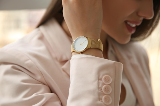 Woman with luxury wristwatch on blurred background closeup