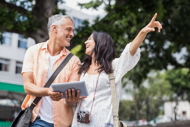 Woman with man pointing in city while using digital tablet