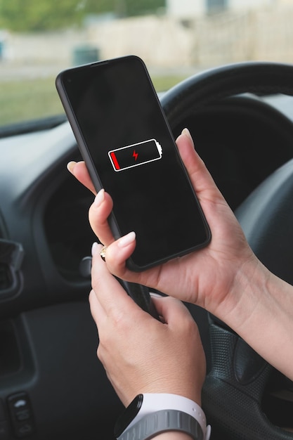 Woman with a manicure holds a smartphone in front of the steering wheel of a car