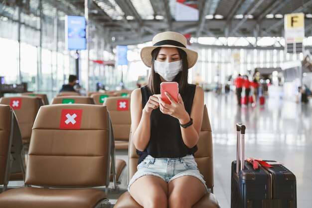 Woman with mask using a phone in an airport