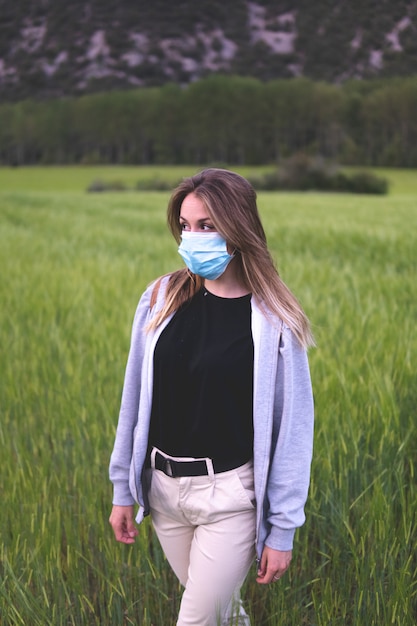 Woman with mask walking through the wheat fields